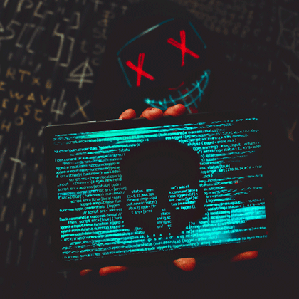Person mit Cybercrime Gesichtsmaske hält einen Bildschirm vor sich auf dem maliziöser Code läuft.
